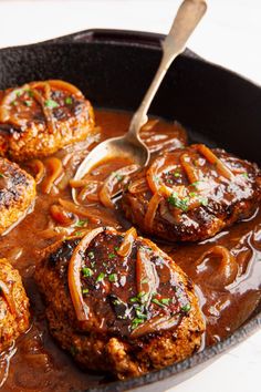 some meatballs and onions are cooking in a skillet with gravy on the side