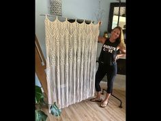 a woman standing in front of a curtain made out of macrame beads and yarn