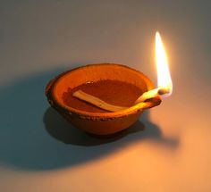 an orange bowl with a lit candle in it