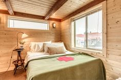 a bed in a room with wooden walls and flooring next to a large window