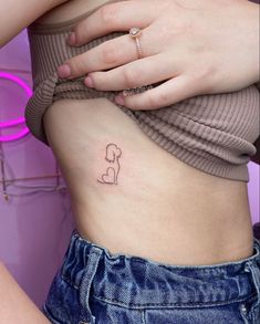 a woman's stomach with a small dog tattoo on the side of her belly