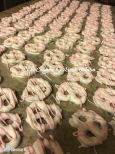 pink and white frosted doughnuts are arranged in the shape of letters on a conveyor belt