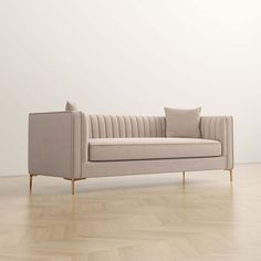 a beige couch sitting on top of a hard wood floor next to a white wall