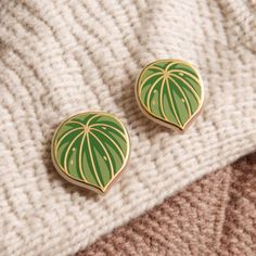 two green leaf shaped pins sitting on top of a white blanket