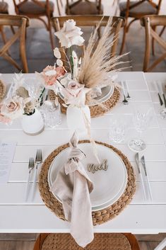 the table is set with white plates and silverware, napkins, and flowers