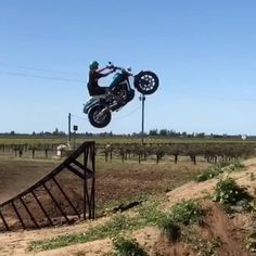 a person on a dirt bike jumping over a ramp in the middle of an open field