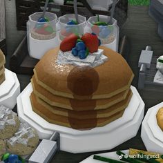 a large stack of pancakes sitting on top of a table next to other food items