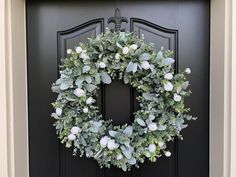 a wreath on the front door of a house is decorated with white flowers and greenery