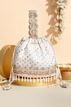 "The Ira chikankari mukaish embroidered bucket bag offers a grandeur experience, by elevating your outfit with a touch of luxury. Immerse yourself in the cultural richness as the chikankari work takes you on a journey, showcasing the intricate hand embroidery of Lucknow in all its splendor. Color: Off-white Embroidered front and back Height: 7\" (18 cm)  Base: 7.5\" x 4.5\" (19 cm x 11 cm) Handle drop: 5.5\" (14 cm) Material : Embroidered pure chikankari with mukaish work, poly satin lining, pearl fringe lace woven, handcrafted pearl handle, dori with pearl & zari tassels." Handmade Clutch Purse, Pearl Fringe, Mukaish Work, Prom Purse, Chikankari Work, Gold Evening Bag, The Ira, Lace Weave, Bridesmaid Favors