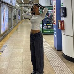 a woman standing in a subway station holding her hair