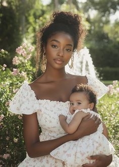 a woman in a white dress holding a small child with her arms around her chest