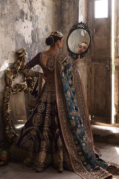 a woman in an elaborate dress looking into a mirror