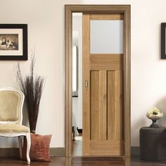 a white chair sitting in front of a wooden door next to a vase with flowers