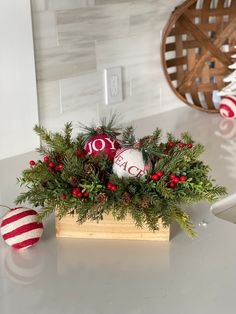 a wooden box filled with christmas decorations on top of a counter next to a red and white ornament