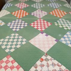 a bed with a green and white checkered quilt on it's headboard