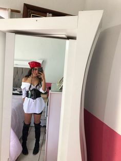 a woman wearing a red hat and white dress is taking a selfie in the mirror