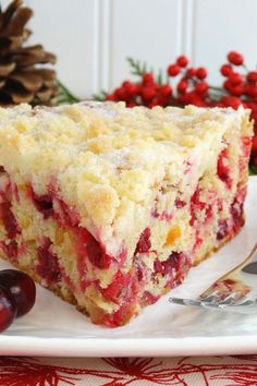 a piece of cake sitting on top of a white plate next to cherries and pine cones