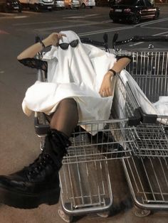 a woman sitting in a shopping cart with her head covered by a white dress and black boots