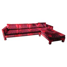 a red and black couch sitting next to a footstool on top of a white floor