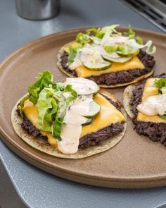 three burgers with cheese and lettuce on them are sitting on a plate