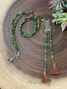 This gorgeous necklace with two tassels is designed with a unique look. It is made from a mix of czech glass beads in different shades of green and shapes. In between the purple beads are brown agate beads for a beautiful contrast. All metal components are silver plated. The pendant connector is vintage inspired rectangle shape that is about 1.25 inches long. The entire length of the pendant with tassels is 6.25 inches long. This necklace is similiar to a lariat style. The necklace length is 27. Cheap Traditional Long Beaded Necklaces, Cheap Beaded Metal Long Necklace, Neaded Necklace With Tassels, Cheap Metal Beaded Long Necklace, Thinks To Make With Old Beaded Necklaces, Cheap Dangling Beads Necklaces As Gifts, Cheap Green Necklaces With Wooden Beads, Traditional Cheap Long Beaded Necklaces, Cheap Green Beaded Pendant Necklaces