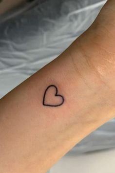 a small heart tattoo on the wrist is shown in black ink, and it looks like an outline