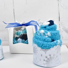 two cupcakes with blue frosting are sitting next to each other in front of a white box