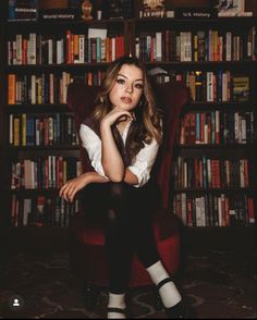 a woman is sitting in a chair with her legs crossed and looking at the camera