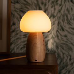 a wooden table with a lamp on it in front of a wallpapered background