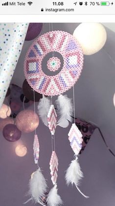 a pink and white beaded dream catcher hanging from a ceiling