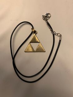 a gold triangle pendant on a black cord