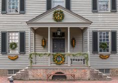 a house decorated for christmas with wreaths on the front porch