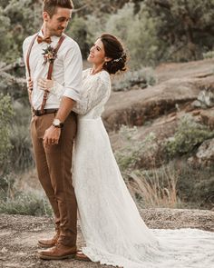 a bride and groom standing together in the woods