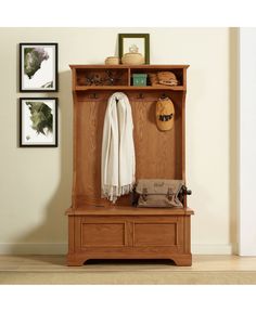 a wooden bench sitting next to a wall with pictures on the wall and a coat rack