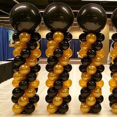 black and gold balloons are arranged on a table