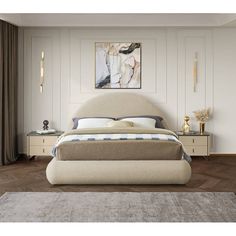 a large bed sitting on top of a wooden floor next to a wall mounted painting