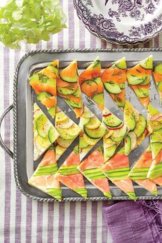 a tray filled with cut up vegetables on top of a purple and white table cloth