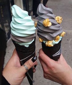 two people holding ice cream cones with different toppings