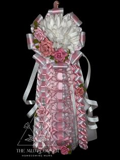 a pink and white flower arrangement in a vase with ribbon around the neck, on a black background