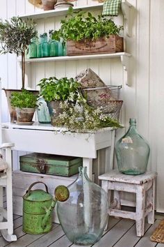 an old white table with some plants on it and two green vases sitting next to each other