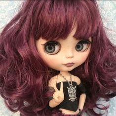 a close up of a doll with long hair and big eyes wearing a black top