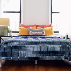 a bed with blue and yellow comforter in front of two lamps on either side of the bed