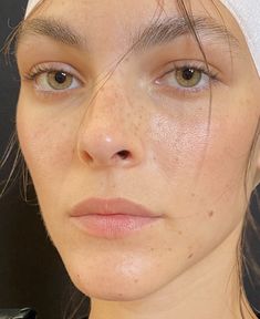 a woman with a towel on her head is looking at the camera and has freckled hair