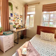 a bed room with a neatly made bed next to a desk and window sill