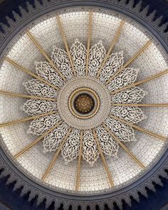 an intricate ceiling in the middle of a building with gold and white designs on it