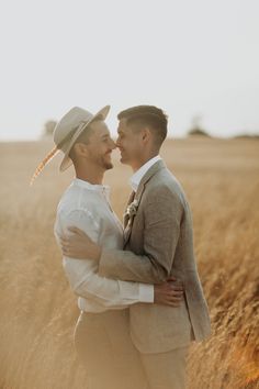 two men are standing in the middle of a wheat field and one is wearing a cowboy hat