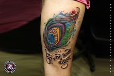 a colorful peacock feather tattoo on the left leg and right leg with words written below it