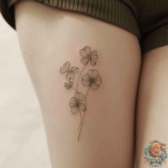 the back of a woman's thigh with four clovers tattoo on her leg