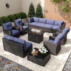 an outdoor living room with blue cushions and furniture on the patio, next to a fire pit