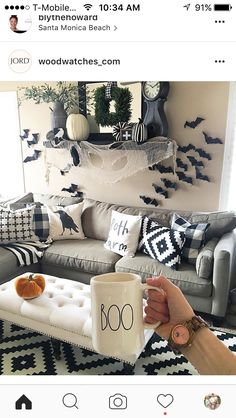 a person holding a coffee mug in front of a couch with halloween decorations on it